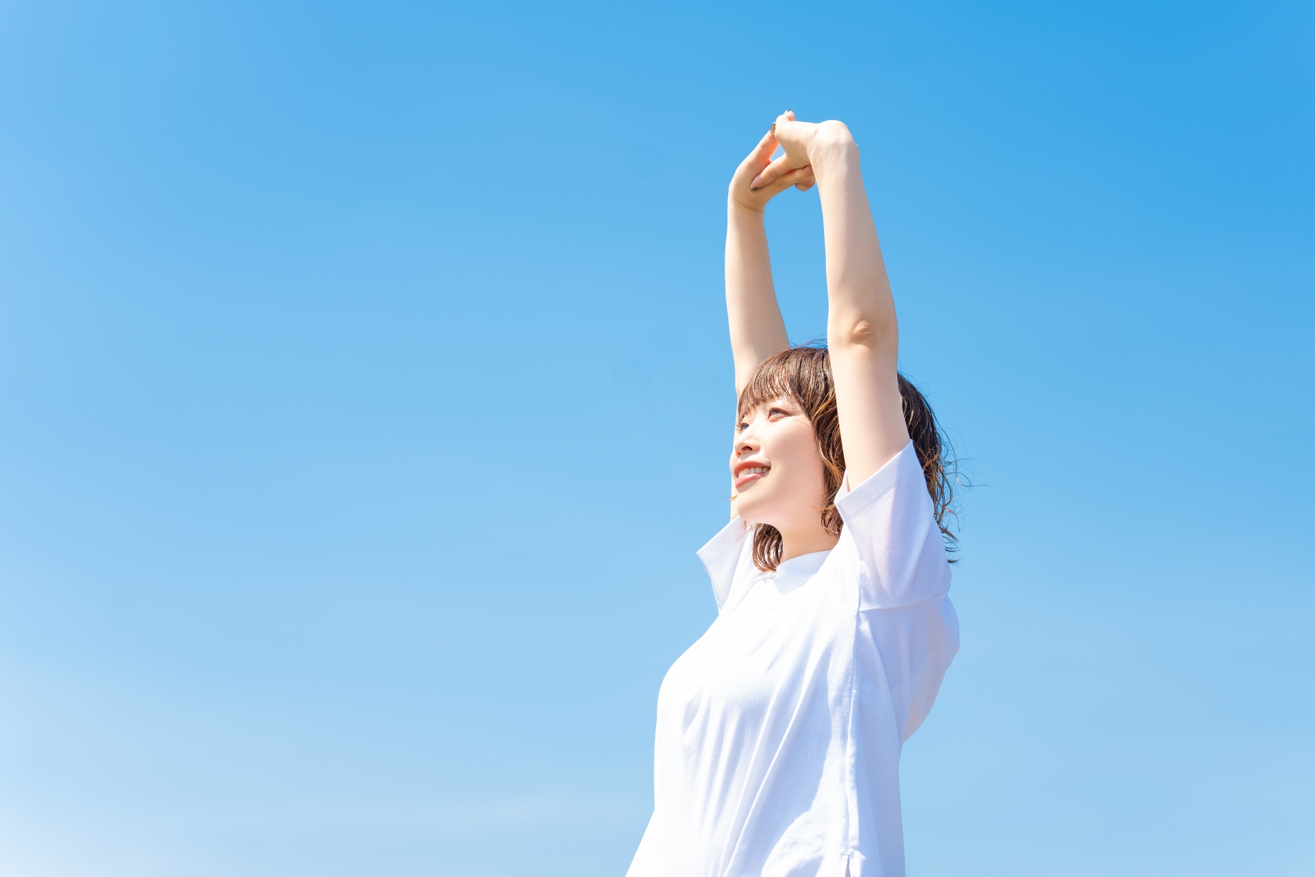 健康的な人が青空の元で背伸びをしている