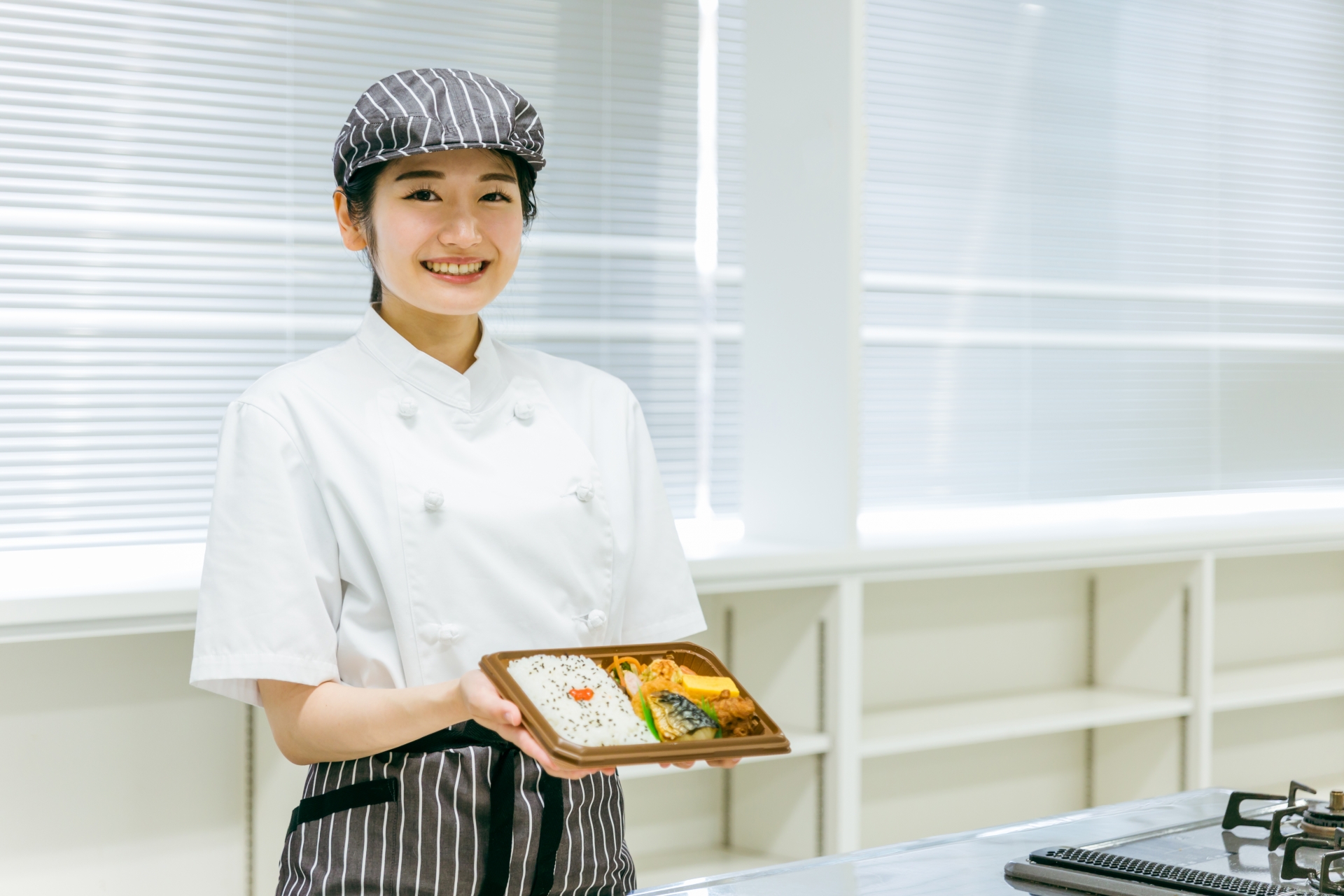 宅食を持つ女性調理師